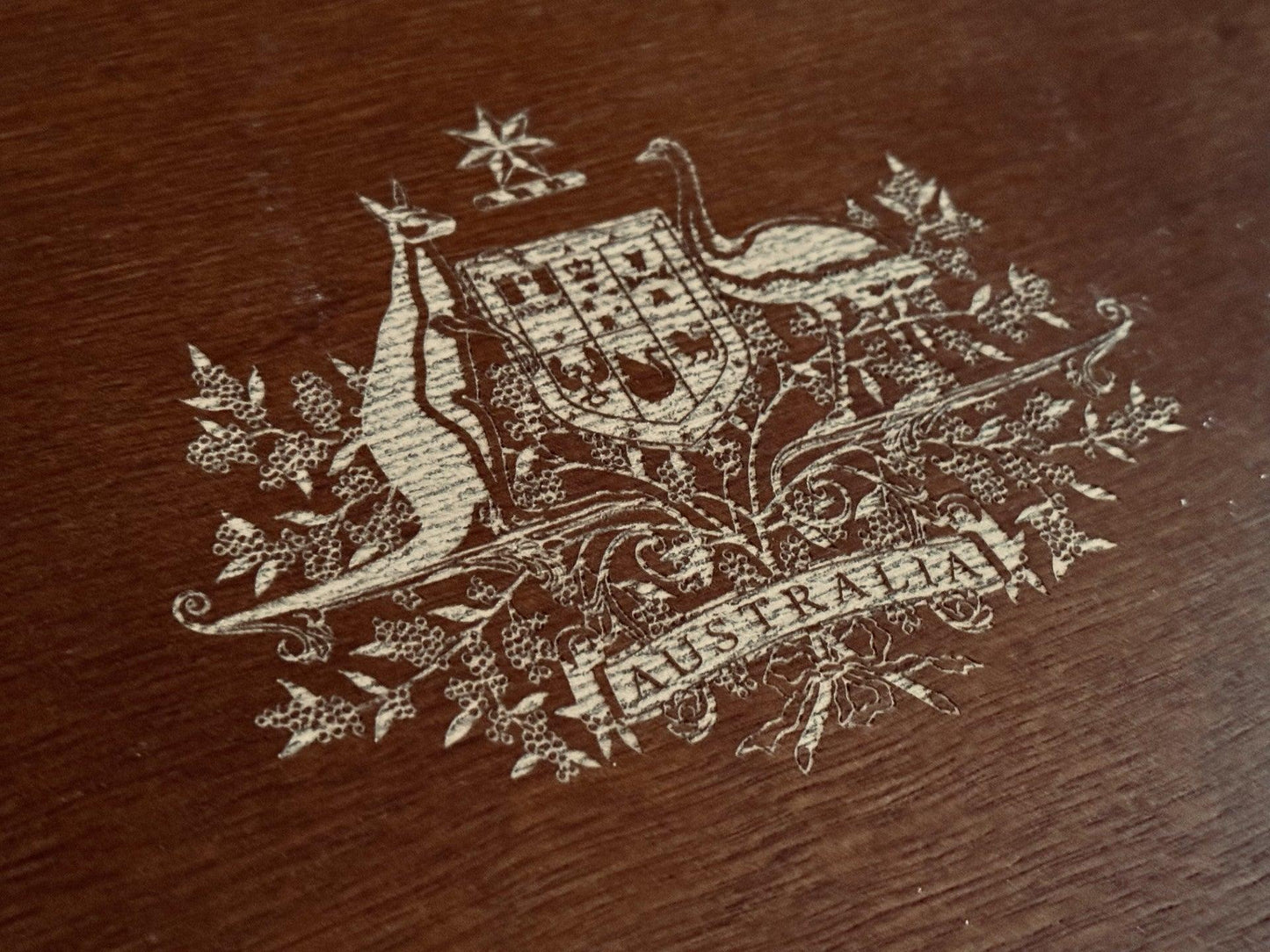 Detail of laser-engraved Australian Coat of Arms on a handcrafted mahogany collectible case lid with a deep walnut finish.