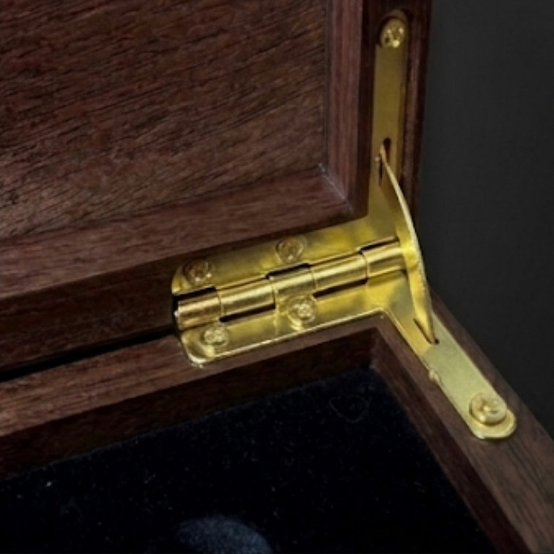 Close-up of a wooden box with a gold hinge on a dark background