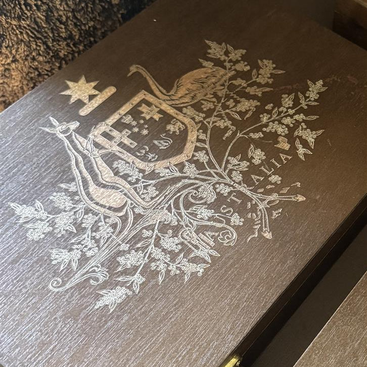 Detail of laser-engraved Australian Coat of Arms on a handcrafted mahogany collectible case lid with a deep walnut finish.